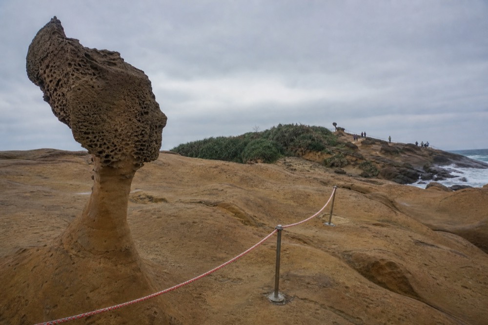 Safety rope barrier marking a protected rock formation area beside the sea