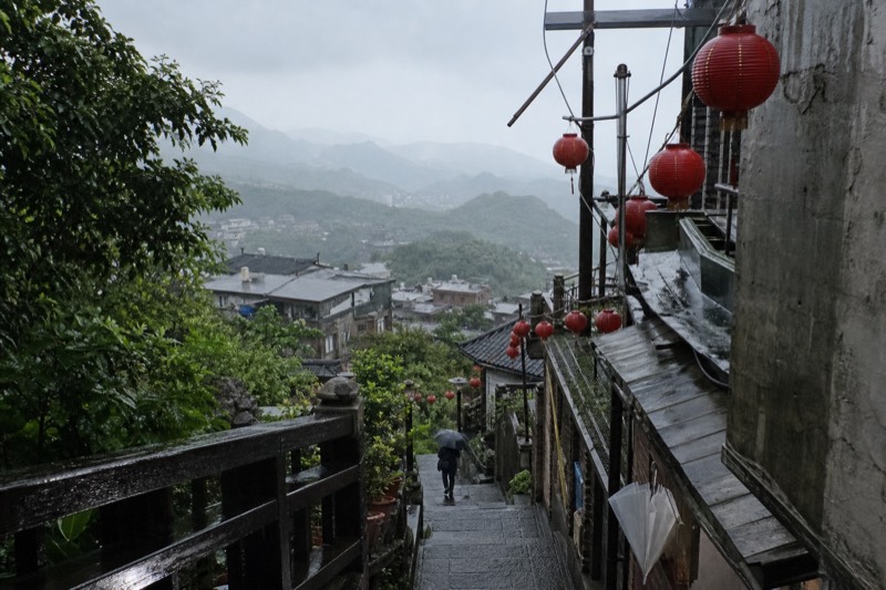 Mist drifting over rooftops at Jiufen, wet stone steps and grey sky above the hillside town in Taiwan