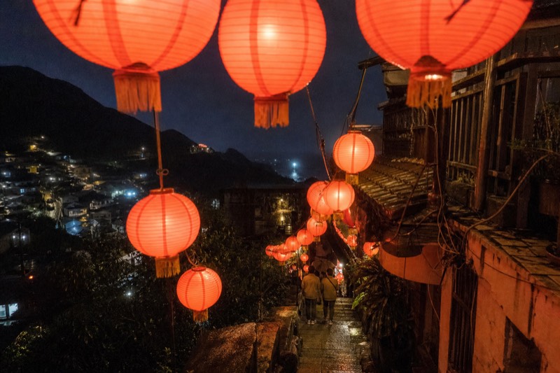 Jiufen after dark, lit lanterns along the lane and house lights on the hillside facing the night sea