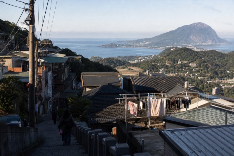 Hillside houses stacked above the sea at Jiufen, the coastline and water below the town in Taiwan